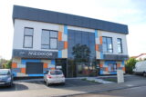 Budynek Medikor z kolorowymi akcentami na elewacji oraz zaparkowanymi samochodami.