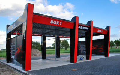 Zewnętrzna stacja myjni samochodowej z dwoma stanowiskami i informacjami na ścianach.